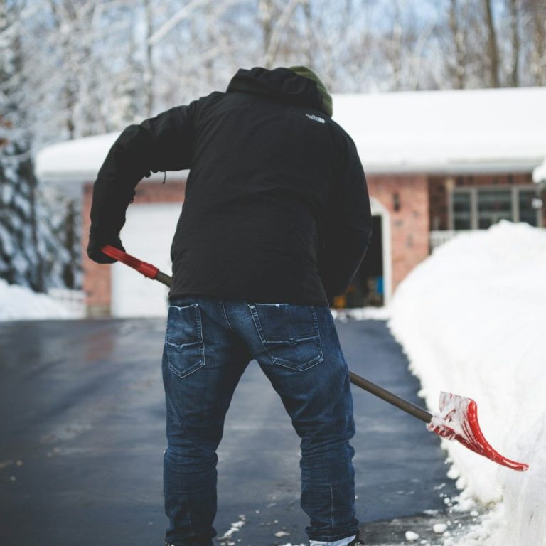 Wir kümmern uns, wenn es schneit! Hausmeister beim Schnee schaufeln in einer Einfahrt