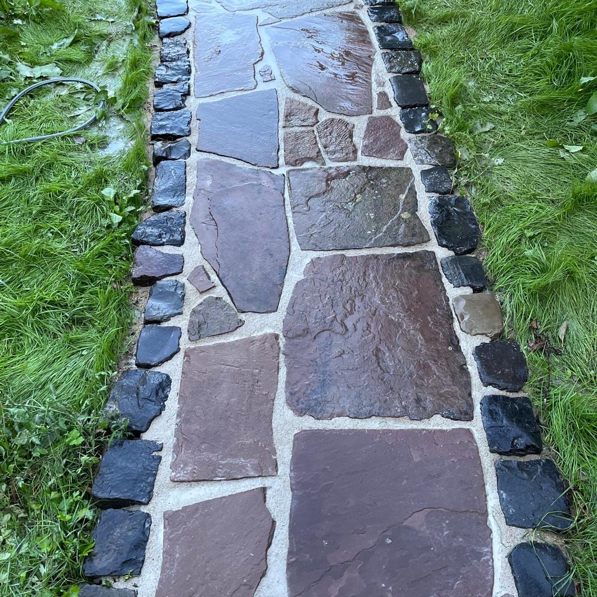 Sauberer Garten, zufriedene Kunden Frisch gereinigter Gehweg aus Polygonalplatten im Gartenbereich